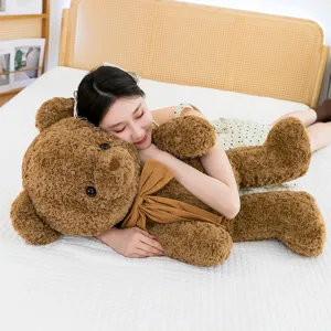 Grande orsacchiotto di peluche marrone con un simpatico fiocco abbracciato su un letto