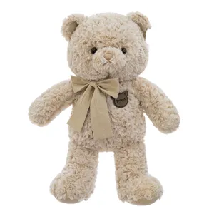 Adorabile orsacchiotto di peluche marrone chiaro con fiocco classico e distintivo sul petto.