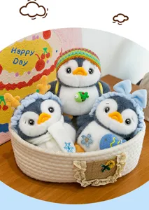 Detail view of three cute penguin plush toy keychains with decorative hats in a basket