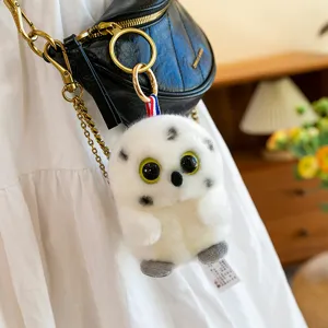 Cute white spherical plush owl keychain with large eyes on a black crossbody bag.