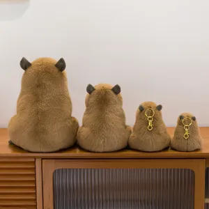 Juego de cuatro lindos peluches y llaveros de carpincho marrón en un estante de madera.