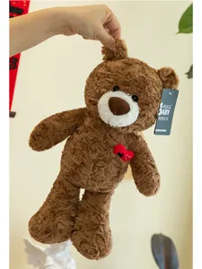Detailed view of a fluffy brown teddy bear plush with a small red heart being held