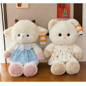 Two adorable plush sheep and bear dolls wearing cute dresses on a wooden surface.