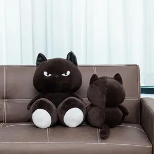 Süße, mürrische schwarze Katzen-Plüschpuppe auf Ledersofa, Vorder- und Rückansicht.