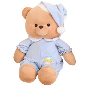 Cute plush teddy bear toy in blue sleeping pajamas and nightcap, soft stuffed animal doll