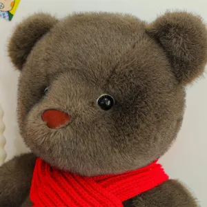 Oso de peluche marrón suave con bufanda roja de punto, vista macro de la textura del pelo