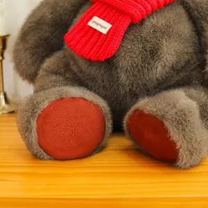 Oso de peluche gris de alta calidad con bufanda de punto roja sobre una mesa de madera