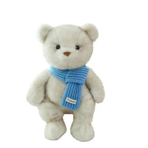 Lindo oso de peluche blanco con una bufanda de punto azul vibrante de accesorio