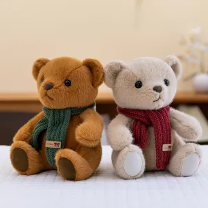 Pair of adorable plush teddy bears wearing green and red knitted scarves on white bed
