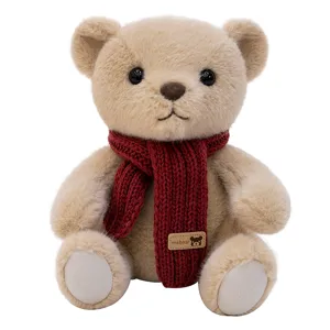 Adorable plush teddy bear stuffed animal wearing a red knitted scarf on white background