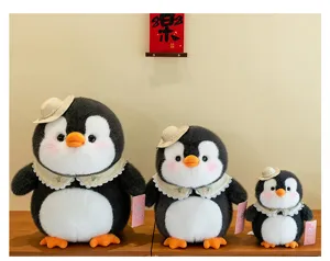 Drei süße Pinguin-Plüschtiere mit Hüten und Spitzenkragen auf Holztisch