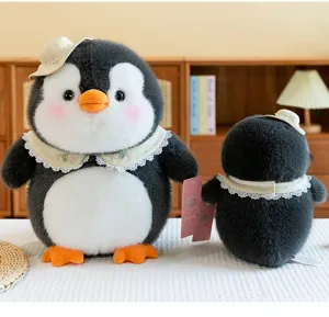 Detailansicht von süßen Pinguin-Plüschtieren mit Strohhüten und Spitzenkragen auf Tisch.