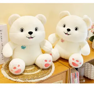 Close-up of two adorable white butterfly teddy bear plush toys sitting on a cozy wooden desk.