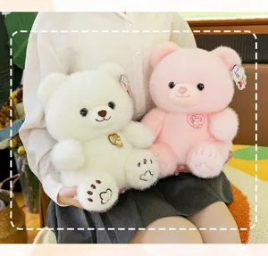 Twee zachte pluche teddyberen in wit en roze met unieke draaibare borstbadges.