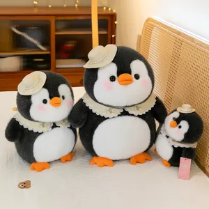 Drei süße Plüsch-Pinguine mit Sonnenhüten und Spitzenkragen auf einem gemütlichen Bett