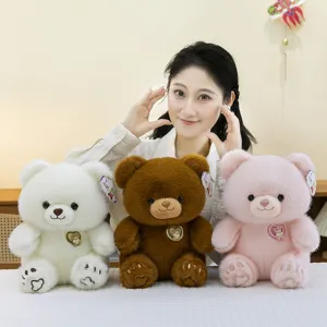 Drie schattige pluche teddyberen in wit, bruin en roze met decoratieve hartvormige emblemen