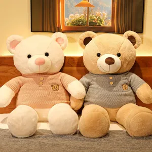 Pair of large teddy bear plush toys wearing cozy knitted sweaters in a warm room setting