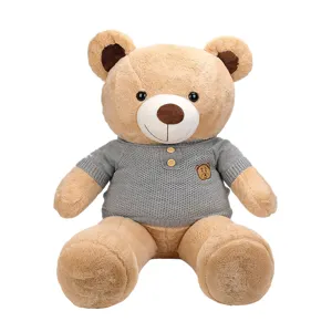 Soft classic teddy bear plush toy wearing a stylish grey knitted sweater on white background