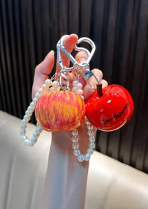 Gros plan du porte-clés pomme avec dragonne en perles et mousqueton en cœur