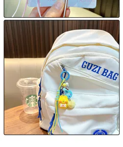 Macro view of cute yellow animal keychain charm hanging on white backpack zipper pull