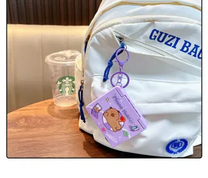 Detailed view of a purple bear phone holder keychain hanging on a white backpack zipper.
