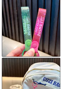 Nahaufnahme von glitzernden Schlüsselanhängern mit 'JUST KEEP DOING IT' Schriftzug.