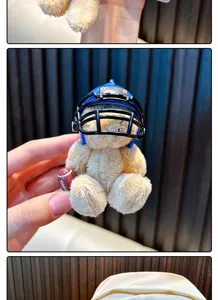 Close-up of a small plush bear wearing a blue football helmet as a keychain charm.