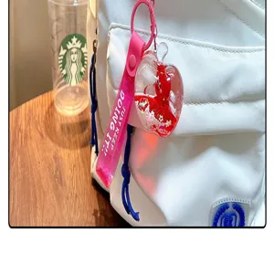 Detail eines roten Apfel-Flüssigkeits-Schlüsselanhängers an einem weißen Rucksack