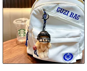 Detailed view of a brown plush teddy bear keychain wearing a black American football helmet
