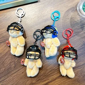 Four plush teddy bear keychains wearing colorful rugby helmets on wood background