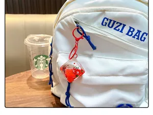 Detailansicht eines Acryl-Weihnachtssocken-Schlüsselanhängers an einem weißen Rucksack.