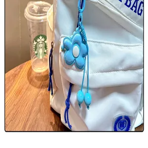 Primer plano de un colgante de flor azul para bolso con cordón azul en una mochila blanca