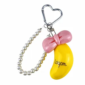 Gros plan d'un joli porte-clés banane avec nœud rose et dimensions 102g