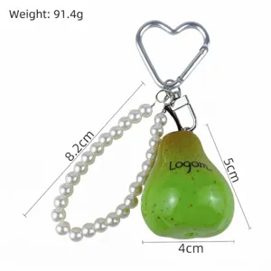 Détail d'un porte-clés poire verte avec perles blanches et crochet en forme de cœur.
