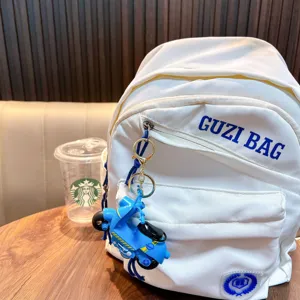 Detailed view of a creative blue motorcycle keychain toy pendant on a white backpack zipper