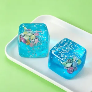 Zwei blaue durchsichtige Stern-Eiswürfel-Squishys mit Muscheln auf weißem Tablett