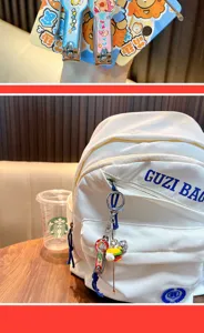 Food-themed mini nail clipper and ear pick keychain hanging on a white backpack