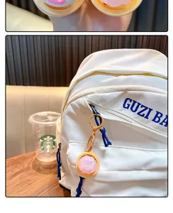 Close-up of cute pink bun stress relief keychain glowing toy on a white backpack