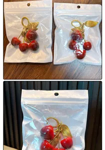 Detailed close-up of realistic red resin cherry keychain stored in a clear plastic gift bag