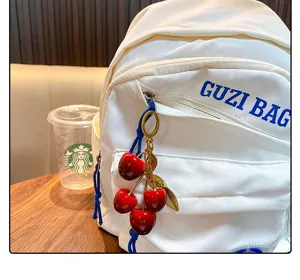 Realistic resin cherry keychain pendant shown as a decorative charm on a white bag