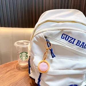 Creative squishy pink dumpling keychain and cute bag charm displayed on a white backpack