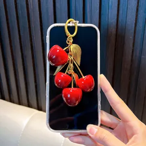Decorative vibrant red resin cherry keychain pendant with elegant gold leaves on smartphone