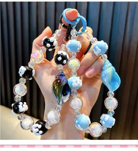 Detail van kralen conch telefoonketting met iriserende kralen en blauwe schelp hanger