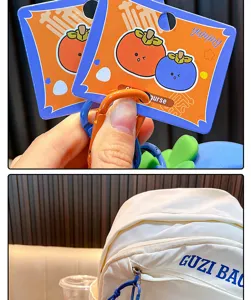 Detail view of a white mini coin purse with GUZI BAG print and cute fruit packaging