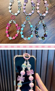 Close-up detail of colorful beaded phone charm with butterfly bows on a clear phone case.