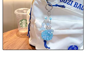 Macro view of blue acrylic shell and fish tail bag charm with a glitter finish