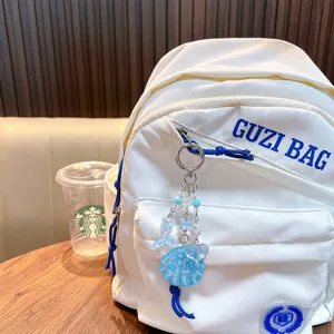 Glitter blue shell and mermaid tail acrylic charm keychain shown on a white backpack.