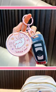 Dettaglio di un portachiavi a specchio rosa con design a gatto e chiave dell'auto