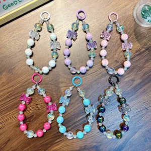 Set of colorful crystal beaded phone straps with bow charms and metal rings on wood