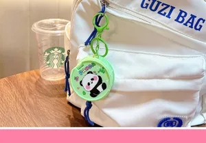 Dettaglio di un portachiavi a specchio panda verde appeso a uno zaino bianco